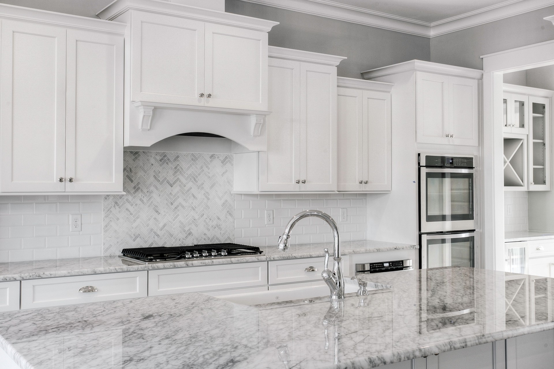 Modern Kitchen With White Cabinetry, Marble Countertops And Gas Range