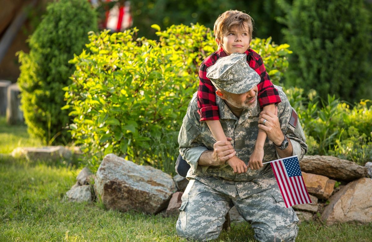 Happy reunion of soldier with family outdoors. Father with his son hugging, holiday, homecoming, emotions, happiness